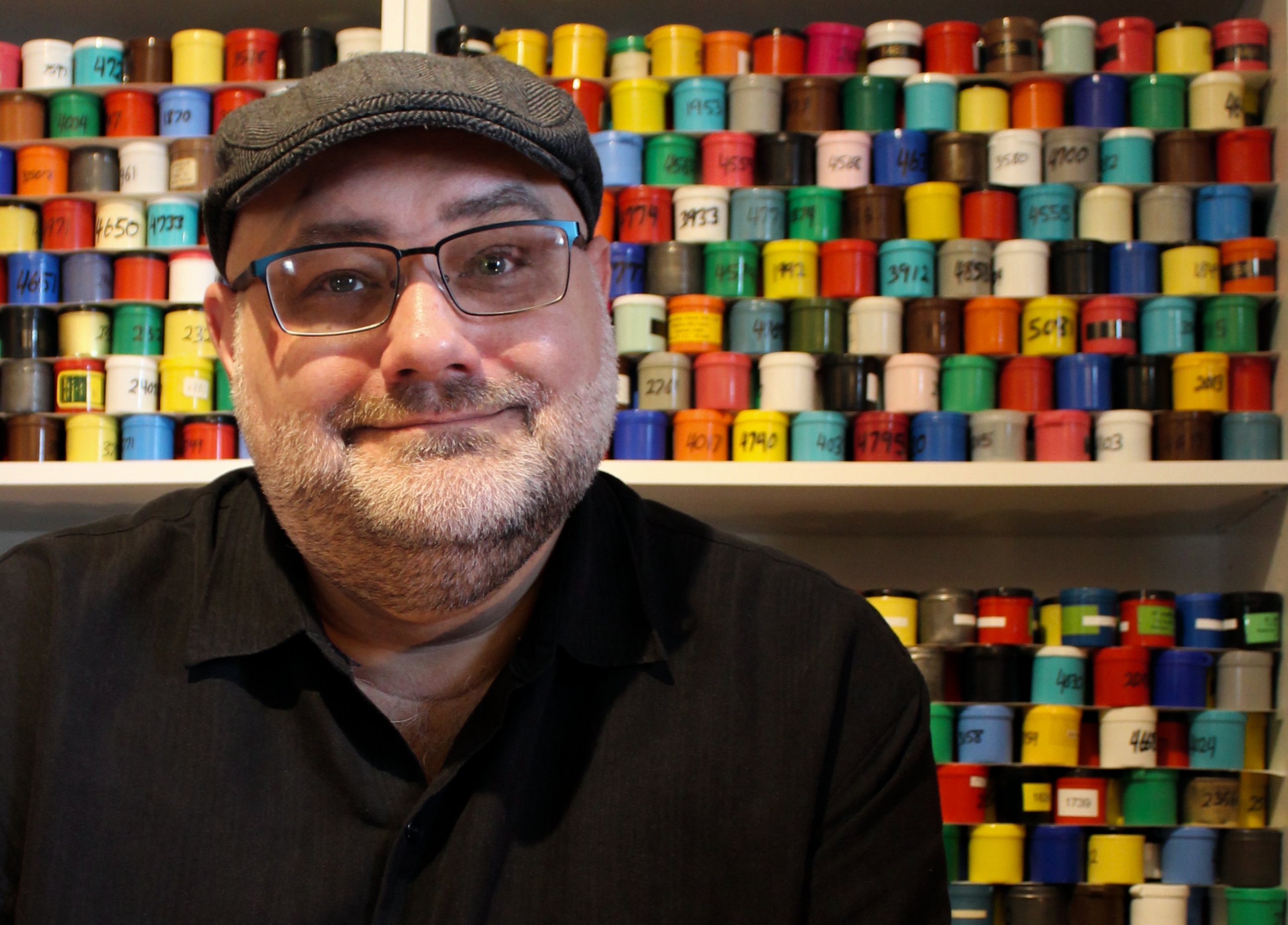 Mark, seated in front of shelves of hundreds of labeled filmstrip canisters
